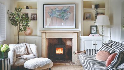 A living room with a striped sofa and a large artwork hung above the fireplace