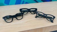 A photo of Oakley Meta HSTN (left), Meta Ray-Ban Display (center), and Ray-Ban Meta Gen 2 (right) smart glasses sitting folded next to each other, showcasing their different designs.