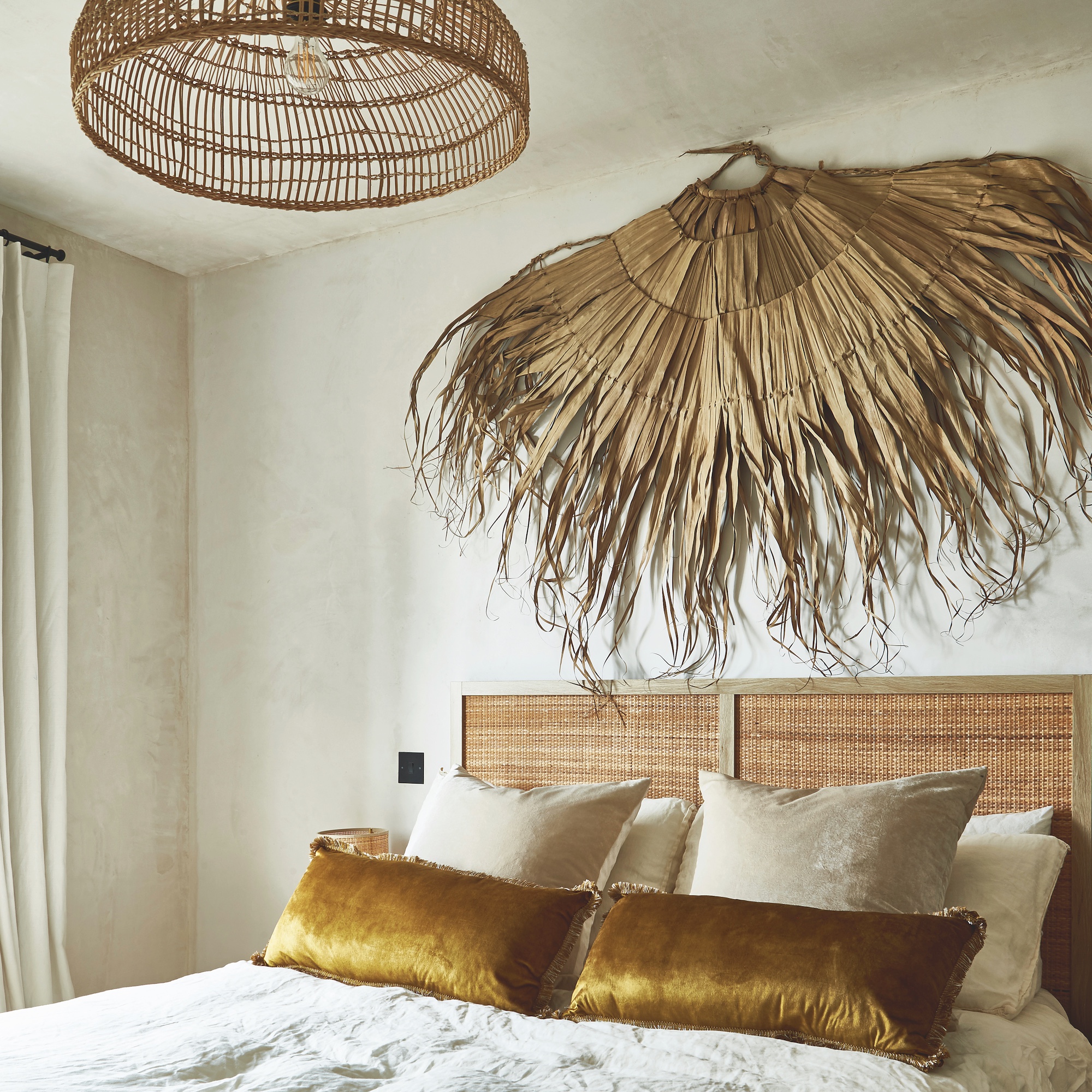 bedroom with woven headboard and raffia wall art fan on wall above bed