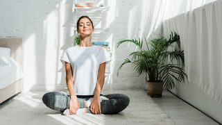 Woman sitting on bedroom floor with eyes closed