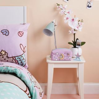 bedroom with bedside table and pink wall and lamp