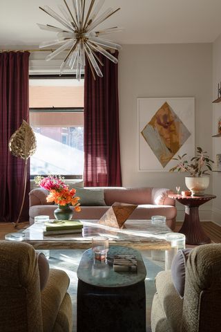 A living room with a pastel pink sofa, a starburst light, and red curtains