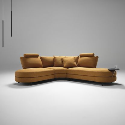 The curved King Living Delta 5 storage sofa in orange with an attached side table in a studio setting
