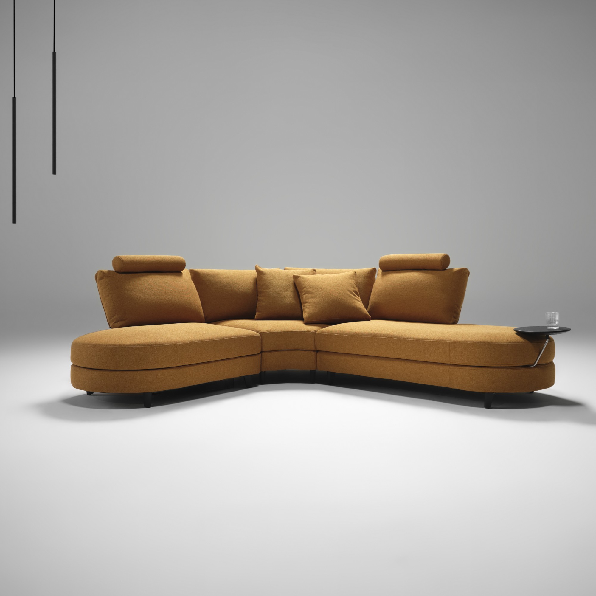 The curved King Living Delta 5 storage sofa in orange with an attached side table in a studio setting