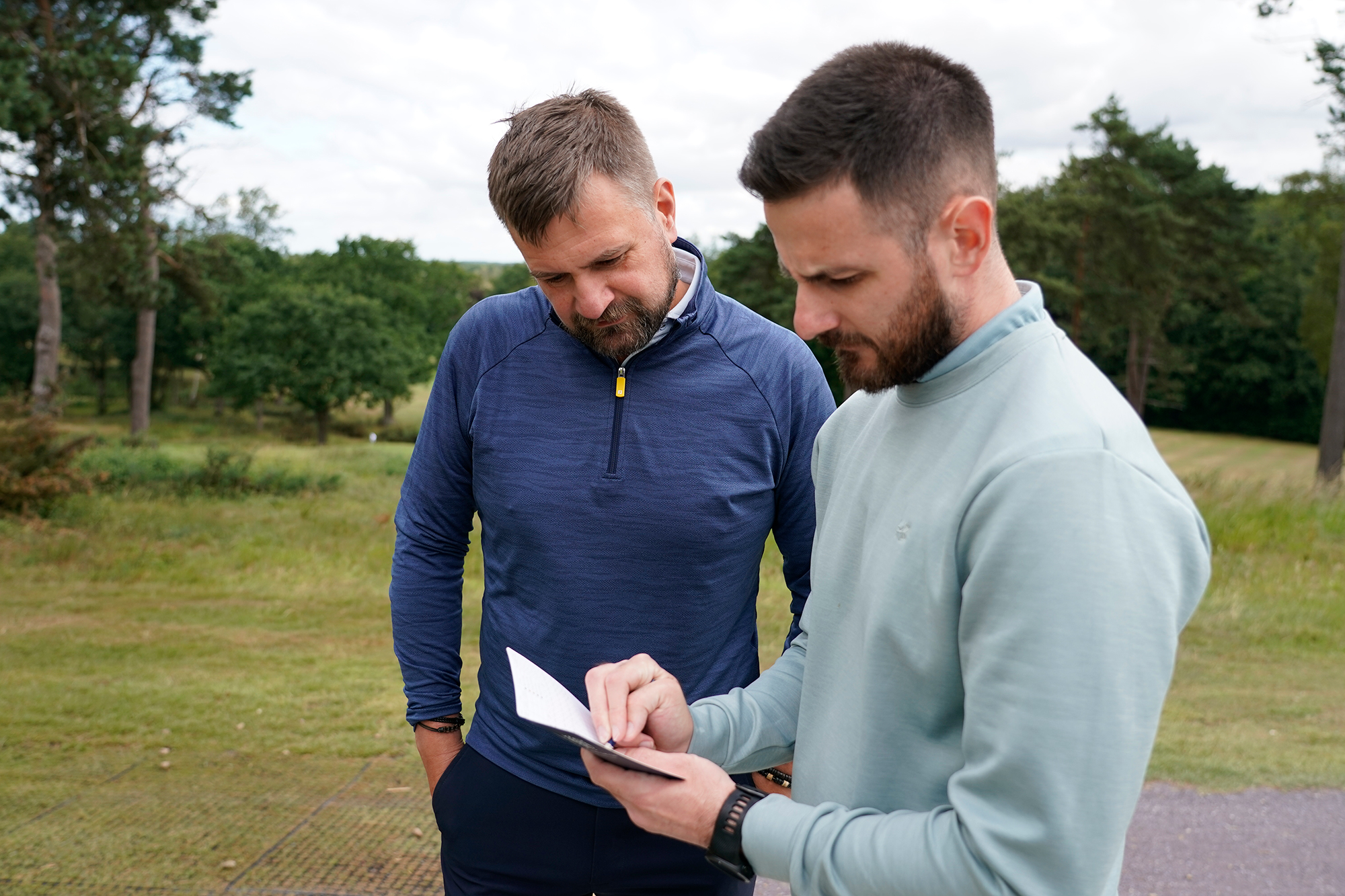 Baz Plummer and Sand Moor Head Pro Alex James looking at a scorecard prior to their round and marking the holes where Baz gets an extra shot, to help make strategic decisions about what constitutes par on each hole for Baz