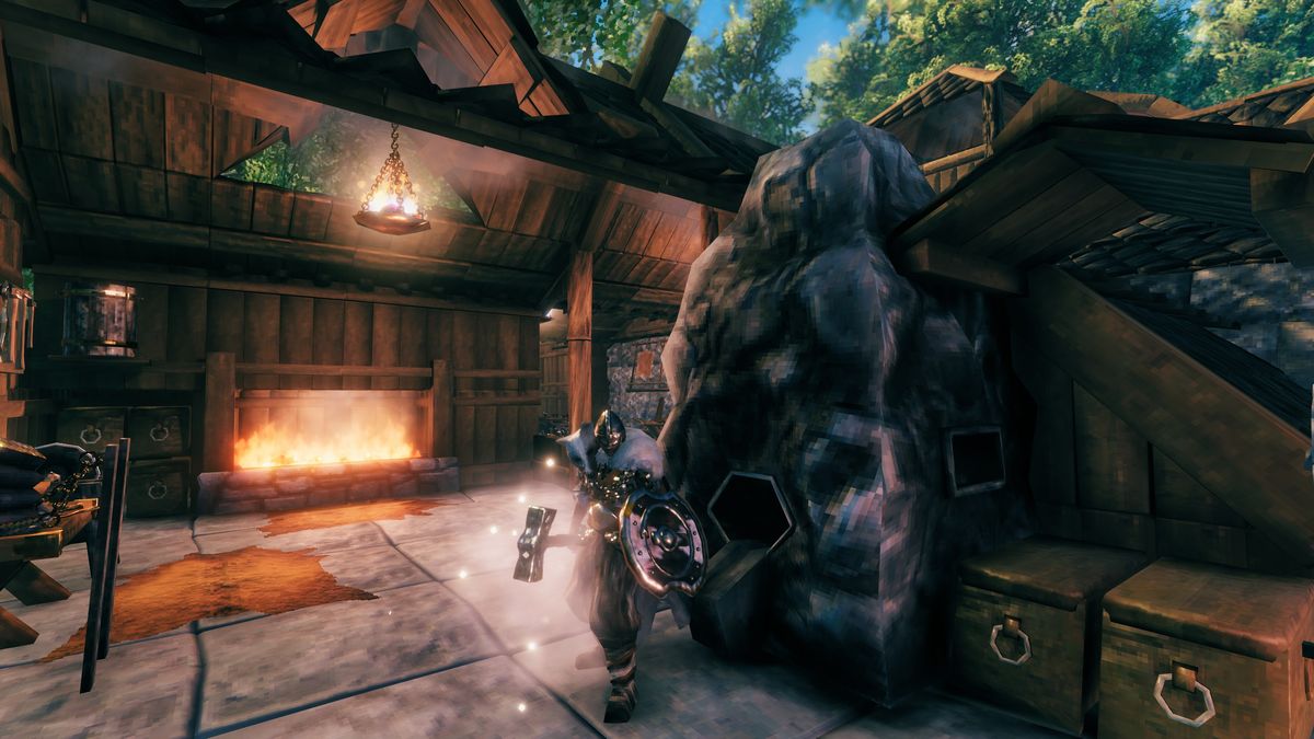 How to get a smelter in Valheim - the Viking character is standing next to a smelter with a fire place behind them and a bronze brazier hanging from the ceiling