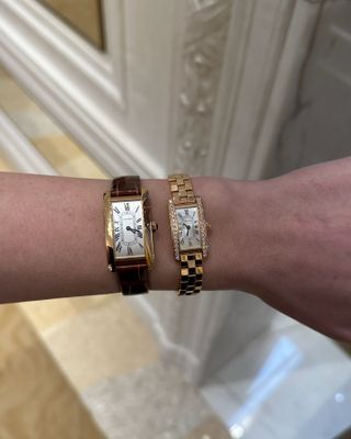 A close up shot of Kristen Nichols' wrist wearing two Cartier Tank watches.