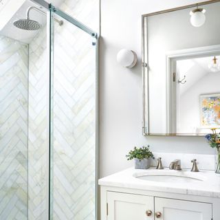 White bathroom with white painted walls and white chevron tiles in the walk-in shower