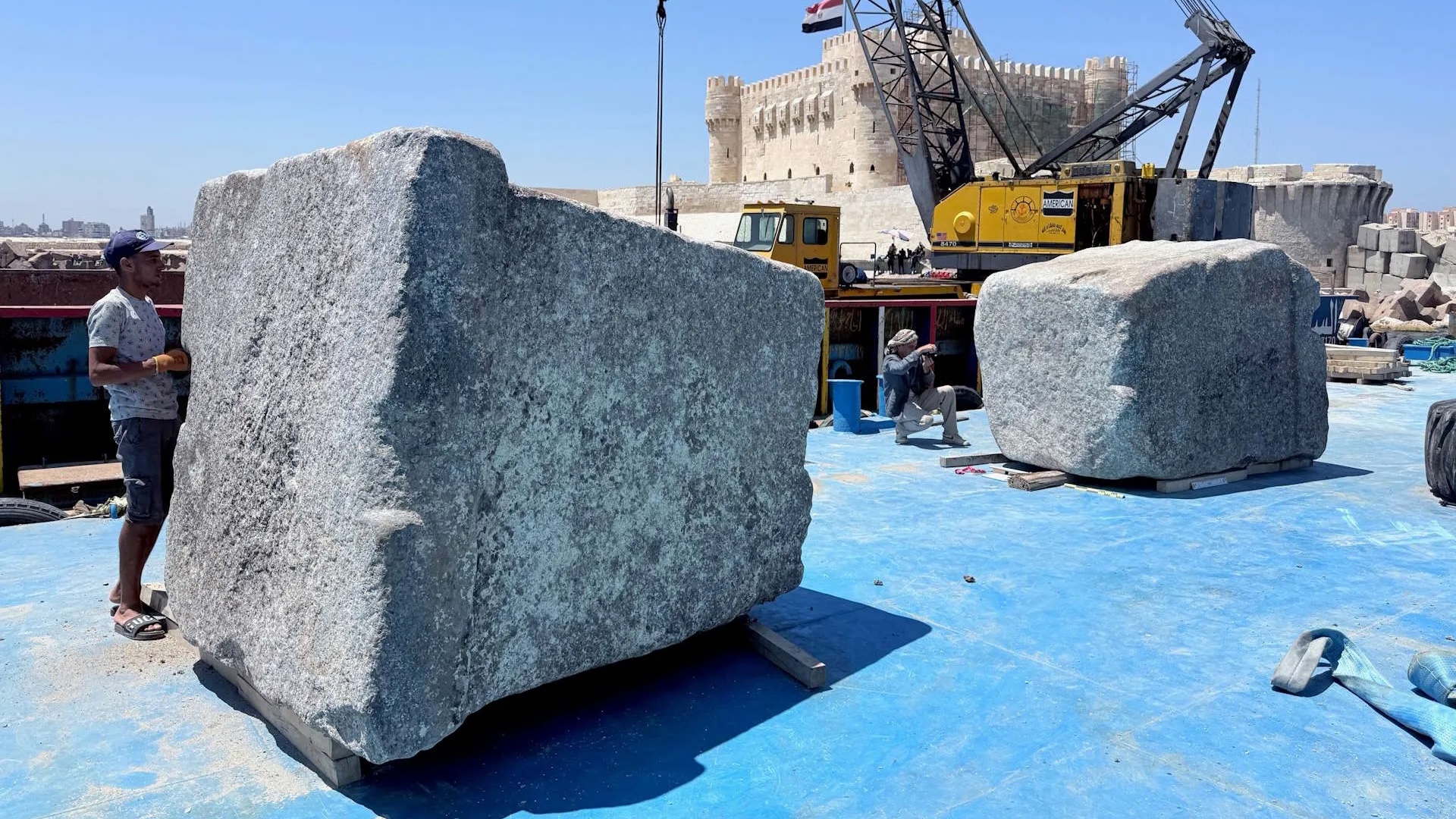 men stand by massive stone blocks in an excavation area