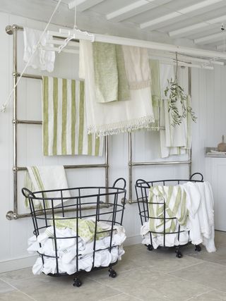 An example of utility room shelving ideas showing green and white laundry hanging on narrow clothes rails