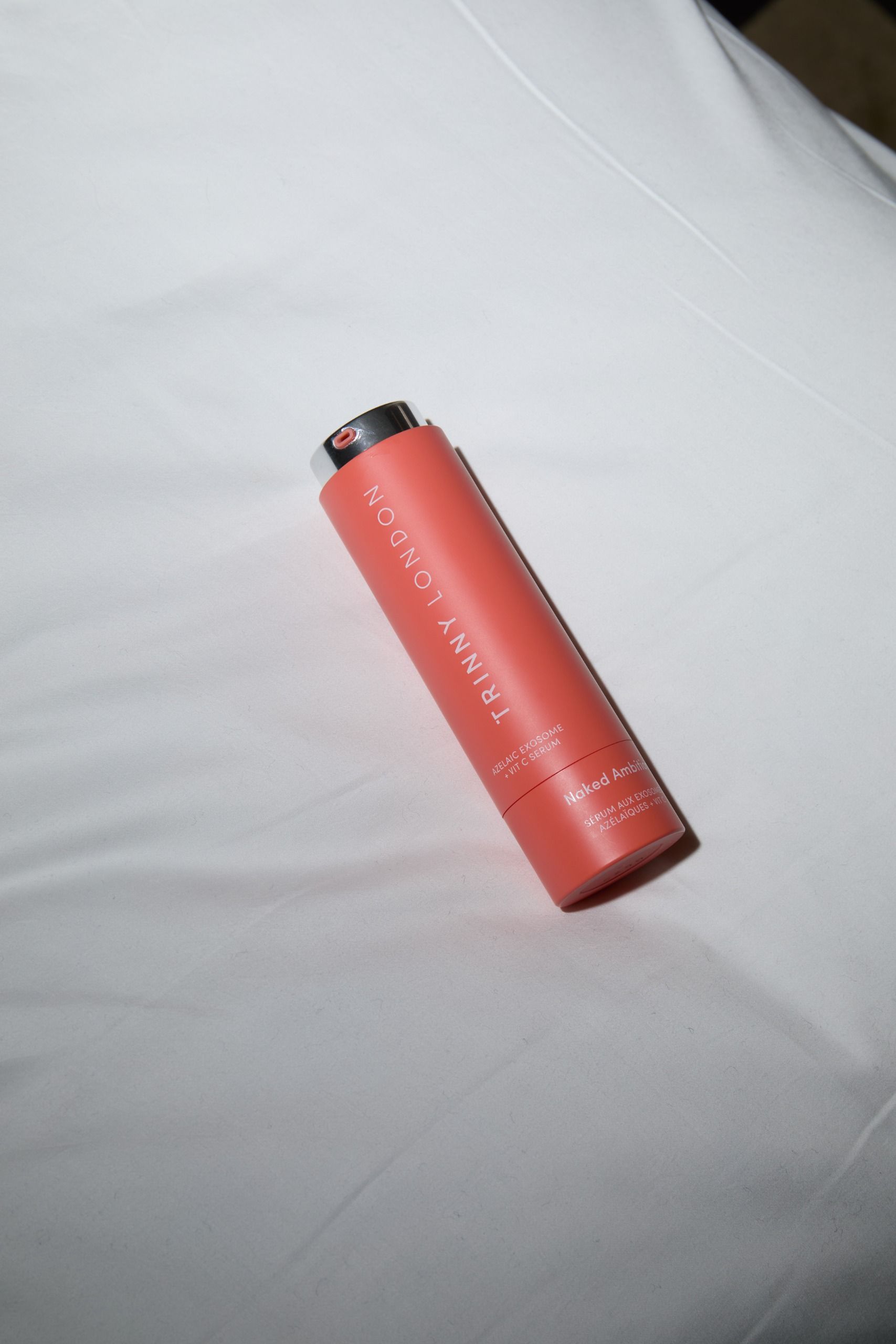 Trinny London Naked Ambition vitamin C and azelaic serum on a bed sheet