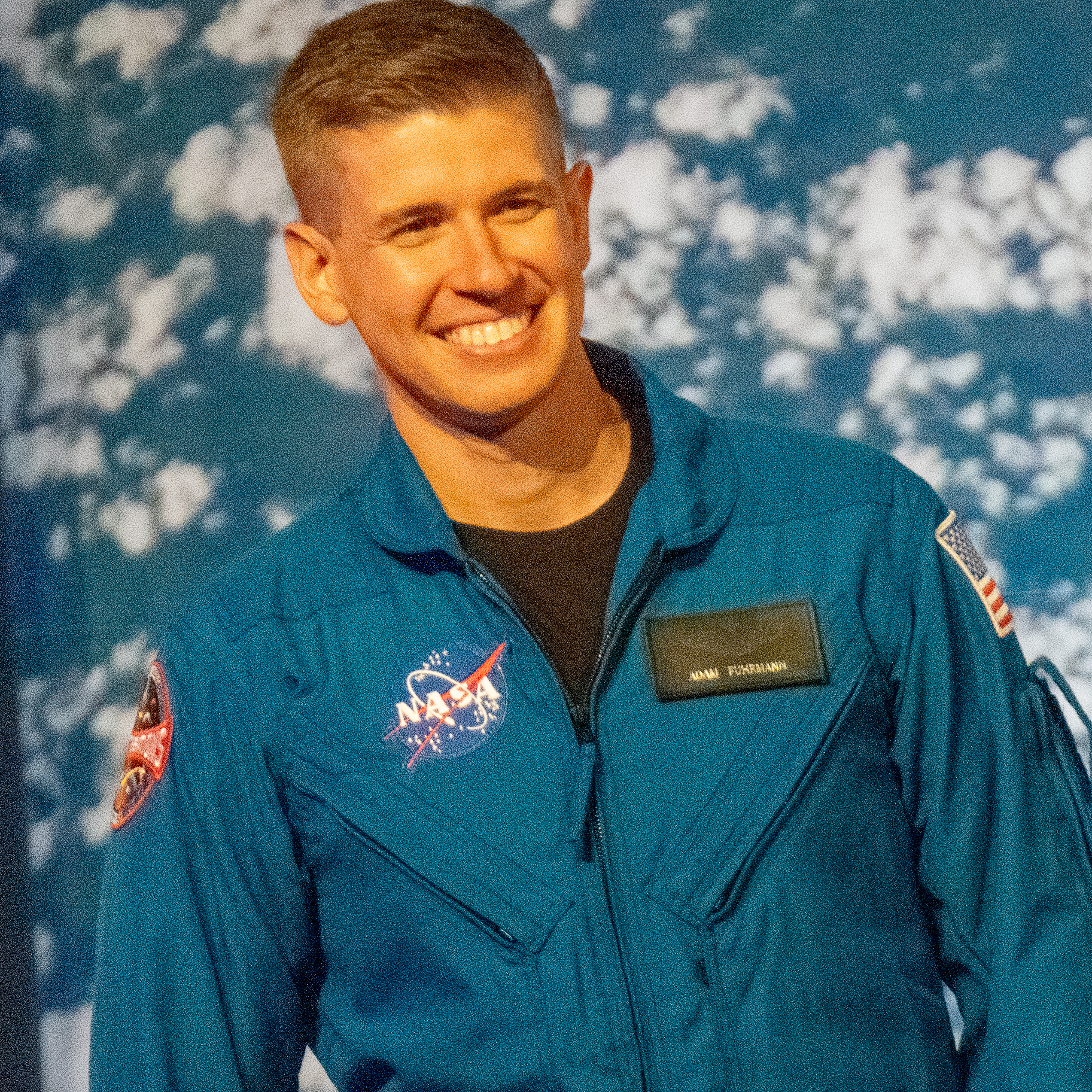 people in blue jumpsuits smile and wave.