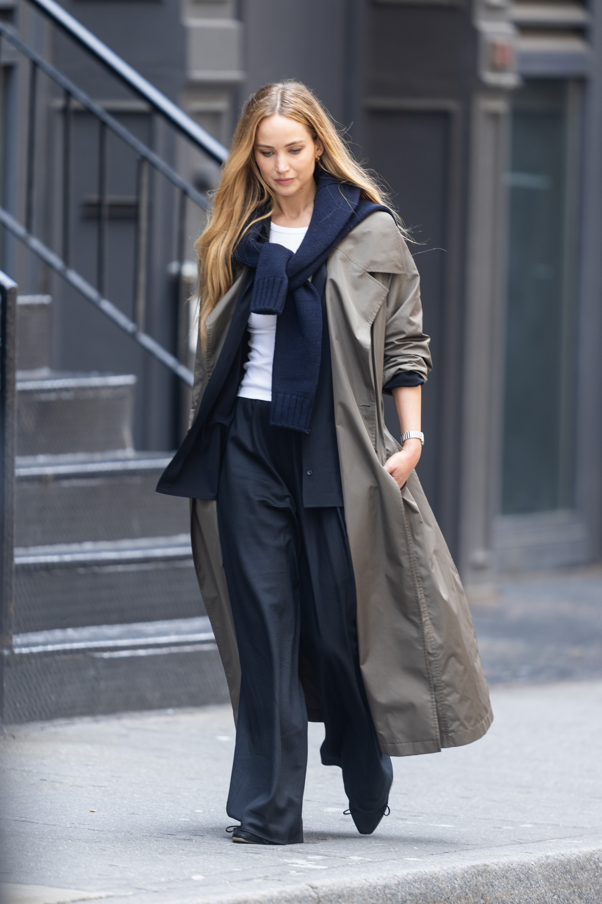An image of Jennifer Lawrence wearing a trench coat, navy coloured sweater, white t-shirt, black wool pants and black ballet flats while out in New York.