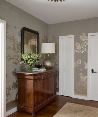 entrance foyer with gold wallpaper with branch pattern and dark wood console