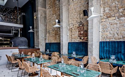 Daroco interior with exposed brick walls and raw cement columns, green marble tabletops and rattan chairs