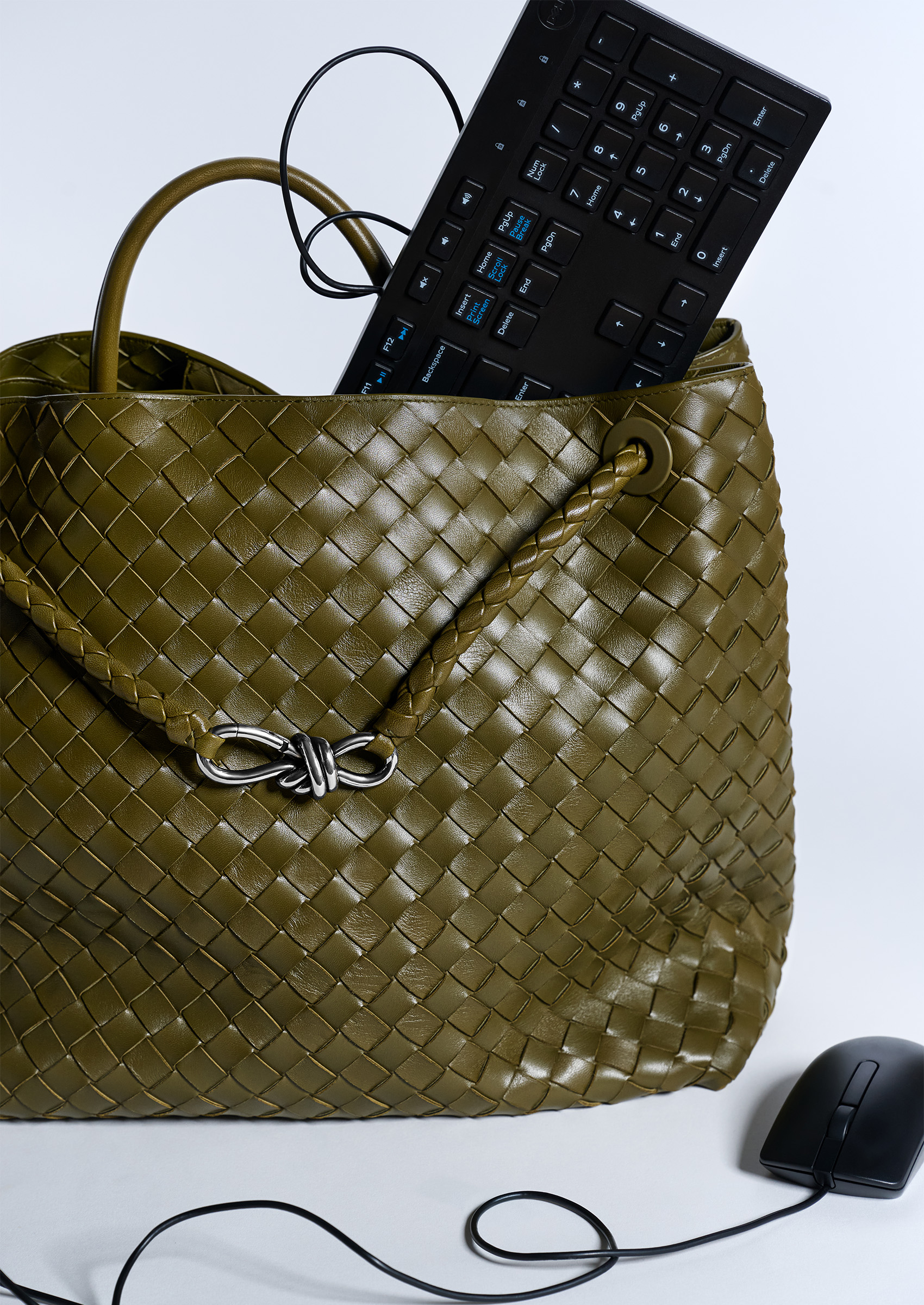 A green woven leather Bottega Veneta bag with a black keyboard and mouse