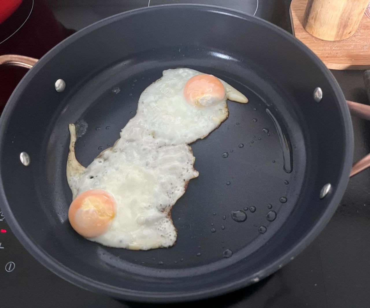 Two frying eggs in a small blue ceramic frying pan