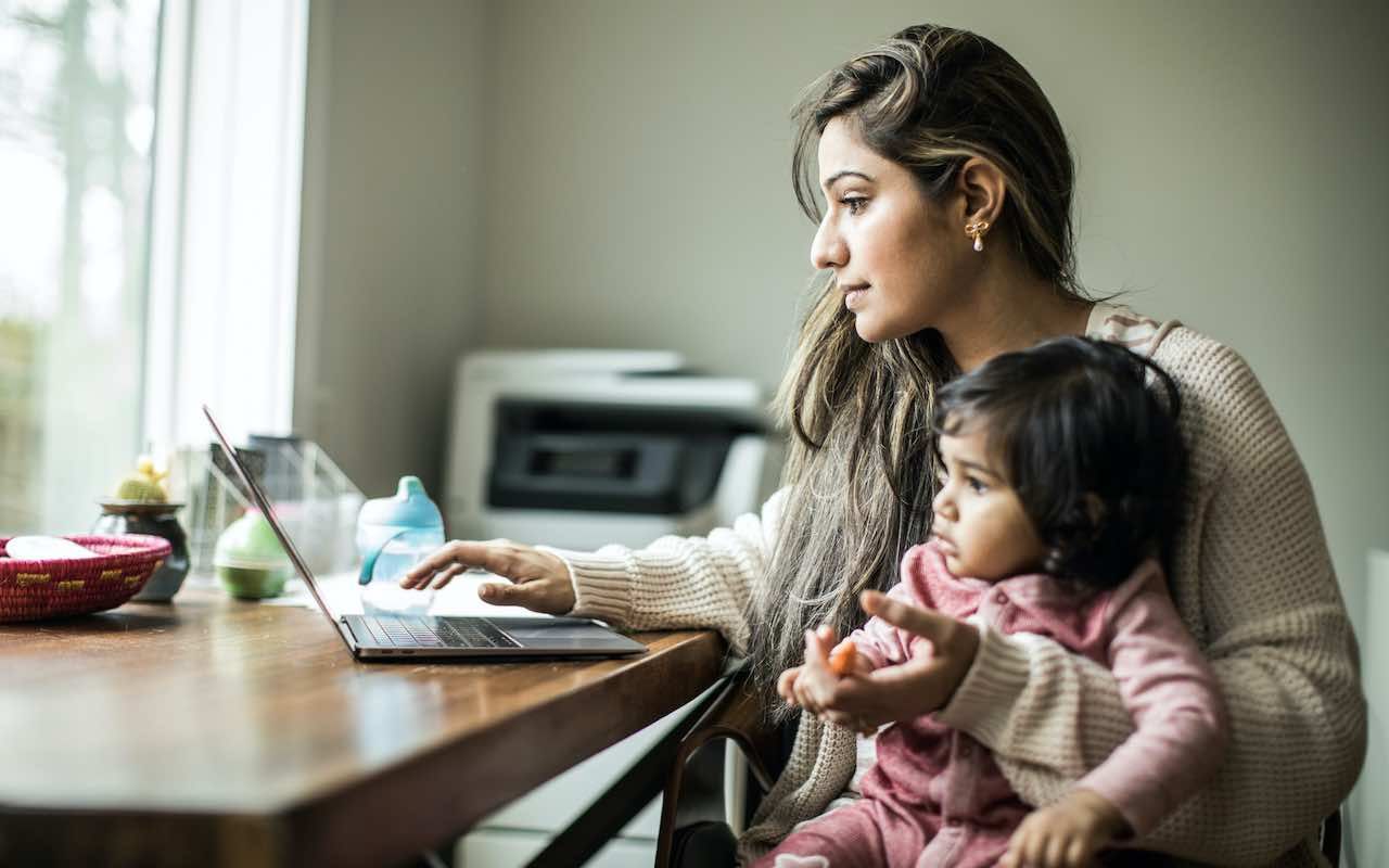 Mother multi-tasking with infant daughter in home office