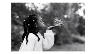 Photograph of a girl blowing seeds from her hand, taken by family photographer Helen Bartlett, one of the speakers on the Canon Spotlight stage at The Photography & Video Show 2026