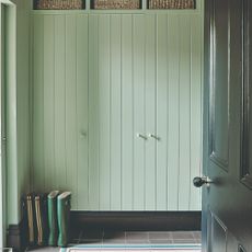 A light green hallway with panelled built-in wardrobes and a dark green open door