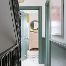 Hallway next to green staircase, looking into a bedroom with green painted doorframes