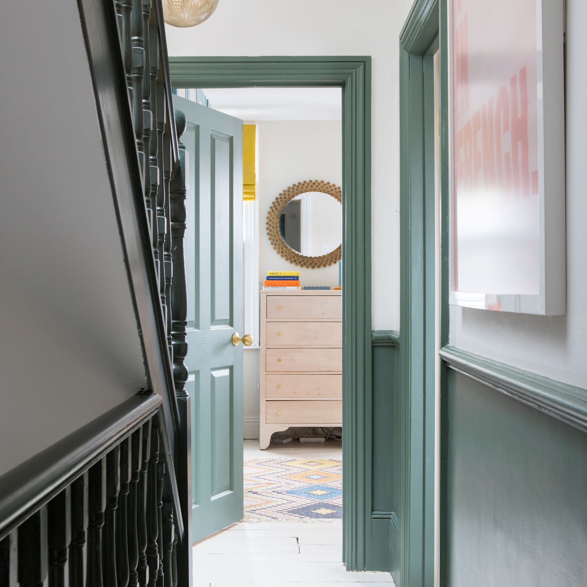 Hallway next to green staircase, looking into a bedroom with green painted doorframes