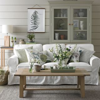 Grey panelled living room with white sofa and grey green woodwork