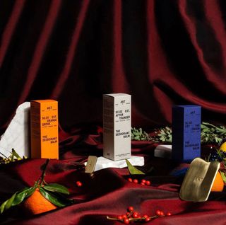 Akt deodorant in orange box, grey box, blue box on dark red curtain