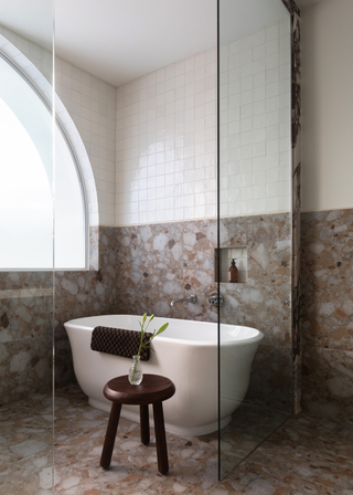 A marble and tile bathroom with a bathtub