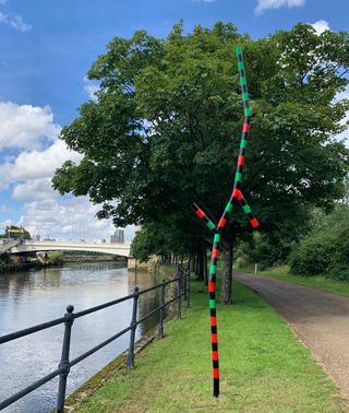 Sculpture made with slender steel tubes, boldly painted black, red and green