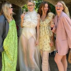 four stylish Scandinavian women pose while laughing at a wedding wearing fun, playful, bright, and chic summer wedding guest dresses
