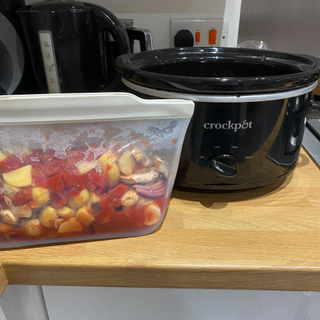 meal prepped food in silicone bag next to crockpot