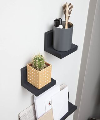 A set of two black adhesive shelves by Command on wall