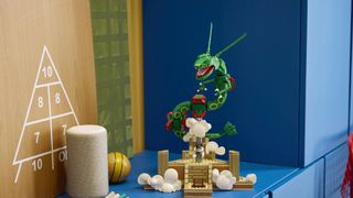 Lego Rayquaza set on a blue sideboard, with a triangle of numbers on a wall beside it
