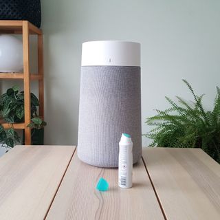 An aerosol deodrant with the cap off on a wooden table in front of a grey Blueair air purifier