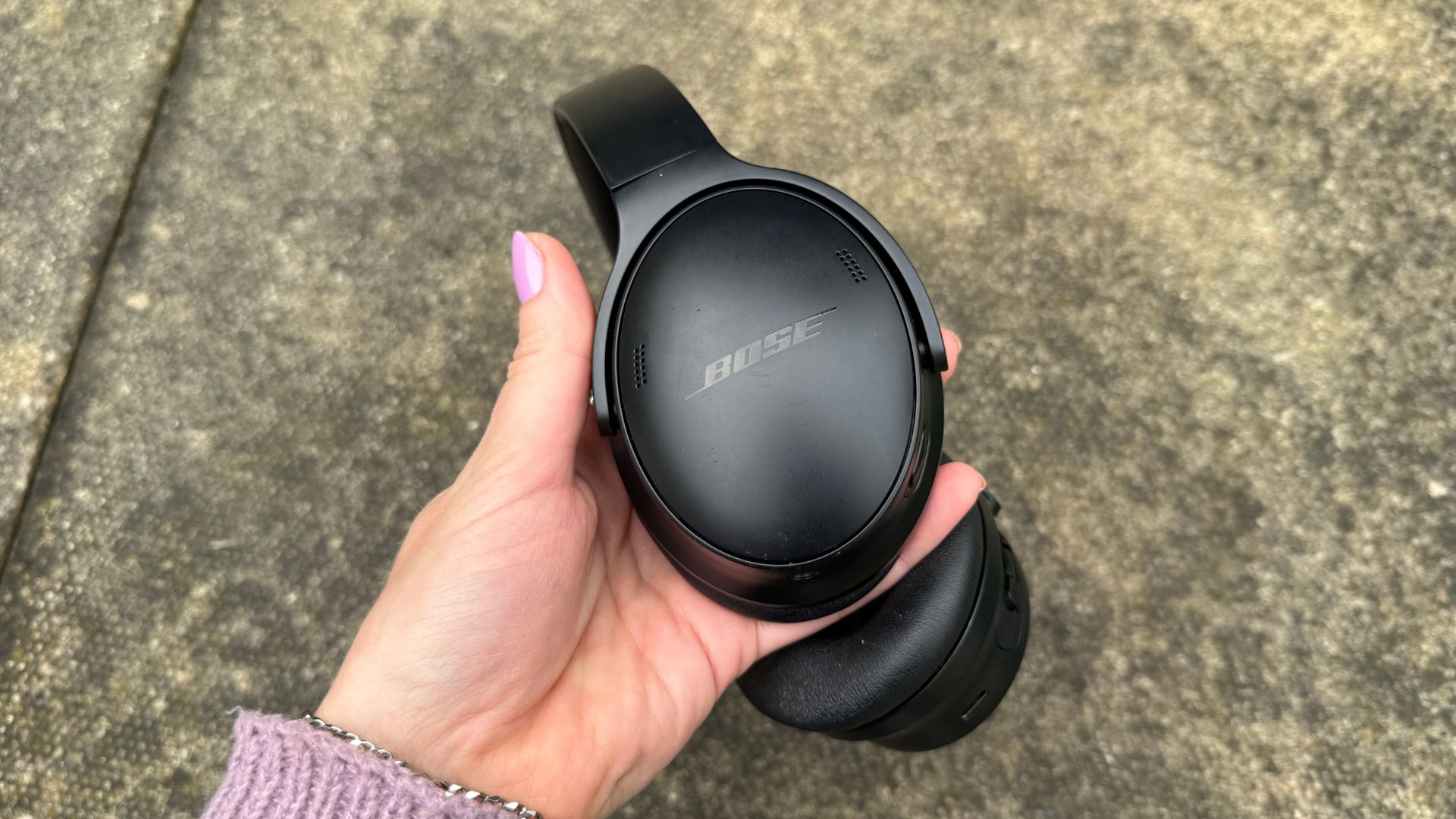 Reviewer holds up the Bose QuietComfort headphones in one hand, showing one side of the headphones.