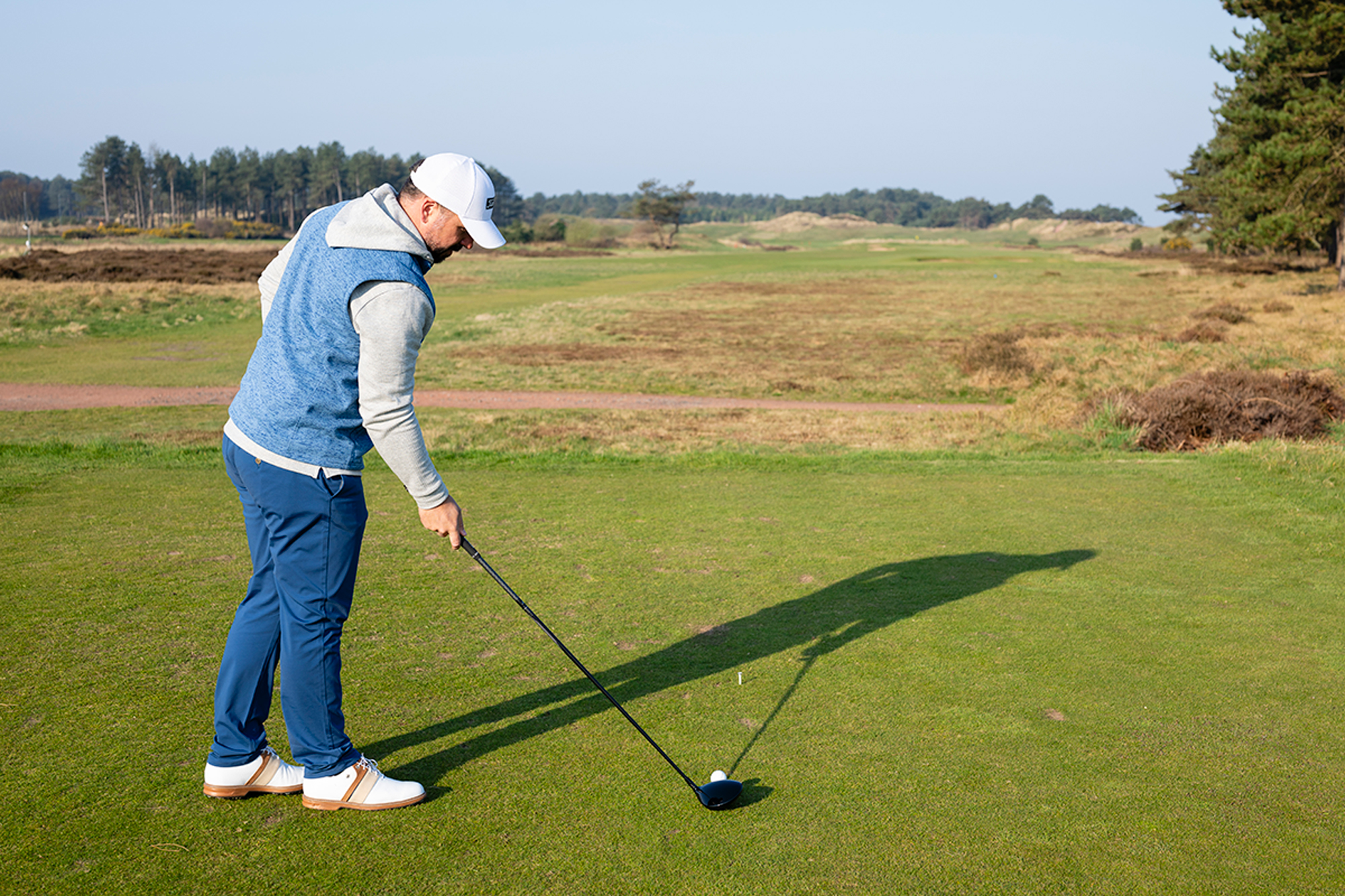 Peter Finch aligning his driver clubface to an intermediate target a few feet in front of him, a tee peg in the ground, in an attempt to hit more fairways with his driver