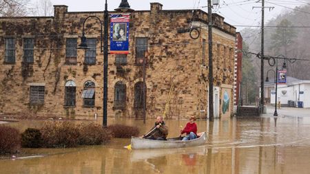 A photograph of two people using a canoe in the flooded main street of Beattyville, Kentucky. 