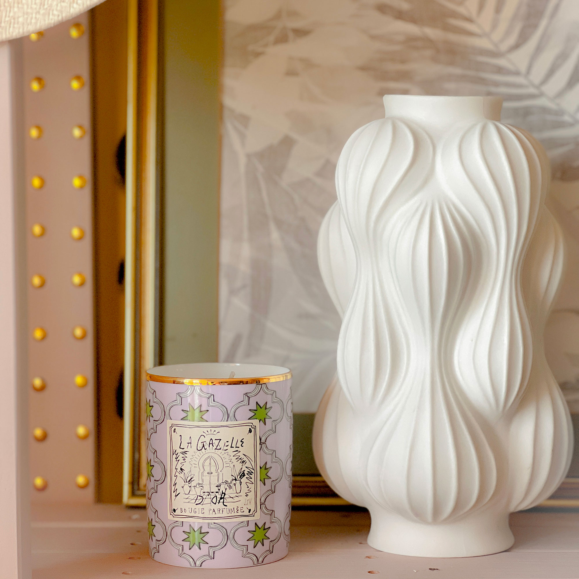 White sculptural vase beside purple and green patterned ceramic candle