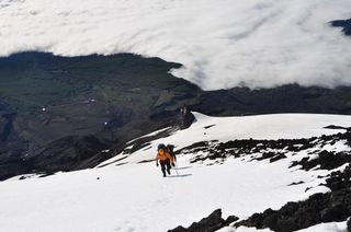 Michigan Tech University graduate students John Lyons and Joshua Richardson hike up the steep snow-covered north flank of Villarrica volcano in Chile.