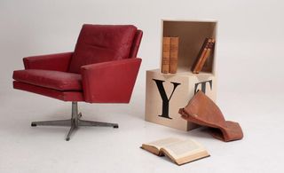 A red leather office pedestal chair and a box of old books