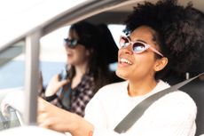 Two young adults sing along with the radio on a road trip.