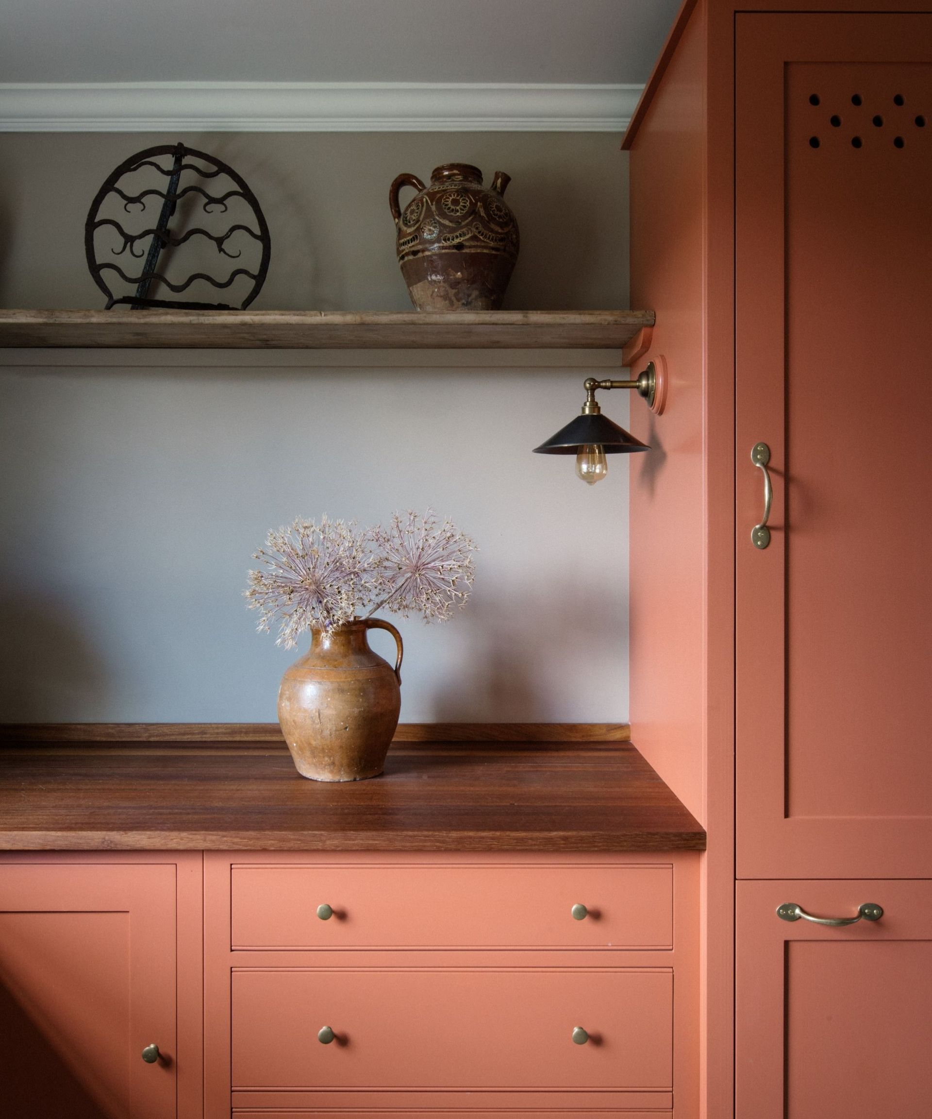 A kitchen with light orange cabinets, wooden countertops, and gray walls