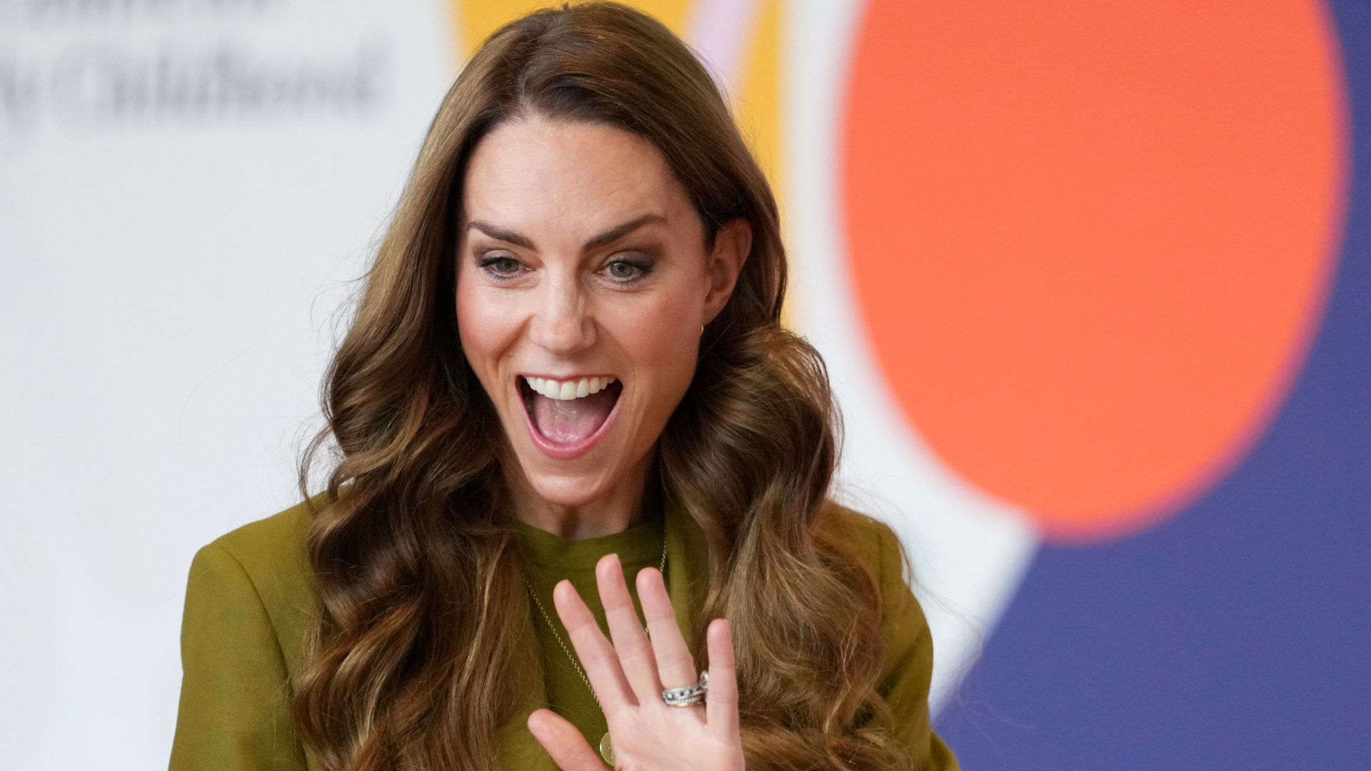 Kate Middleton wearing an olive green suit and waving