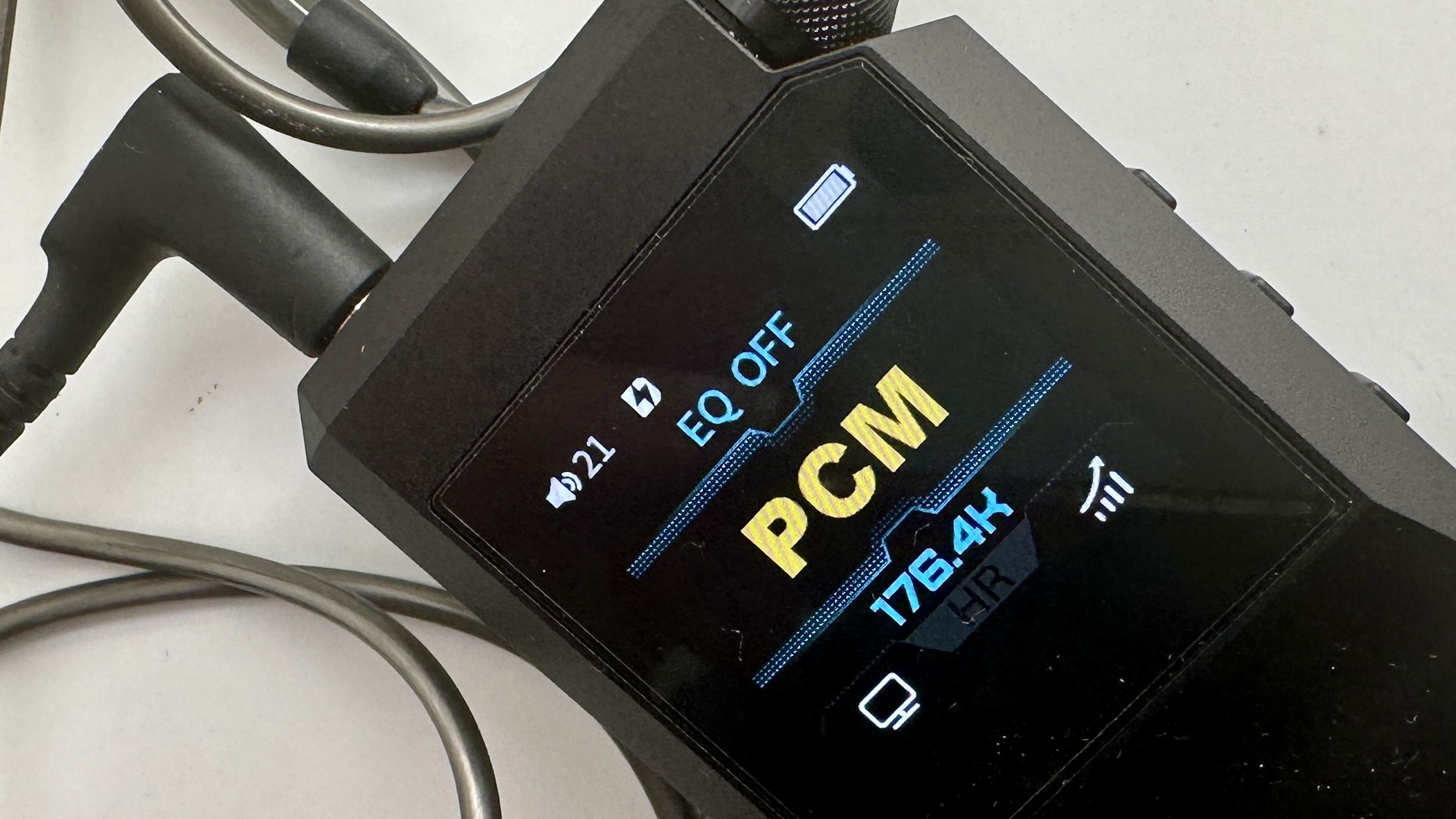 FiiO's BTR17 DAC/amp in black, on a gray table, showing PCM resolution in yellow font