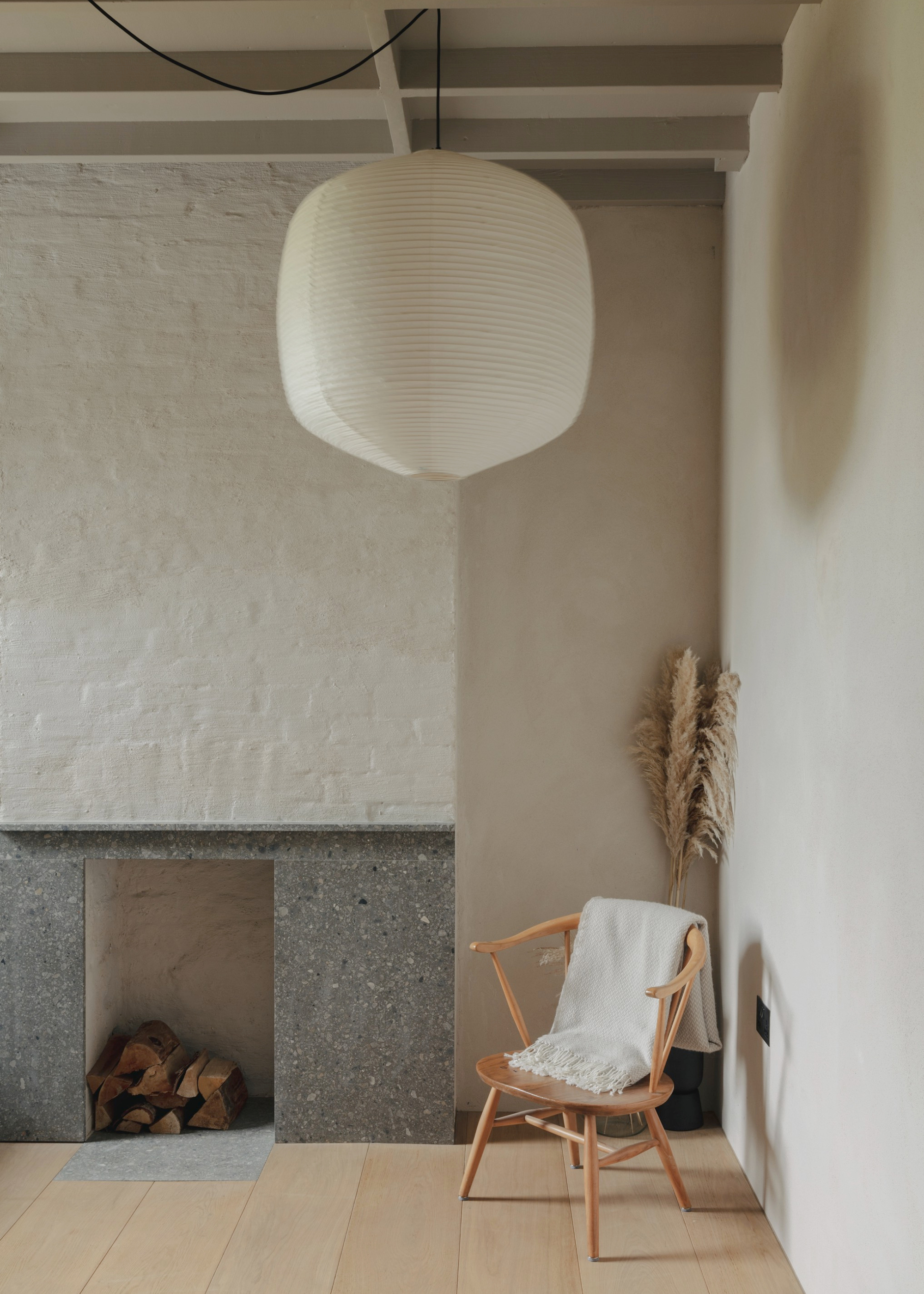 minimalist, simple room with a paper lantern light and stone surround fireplace
