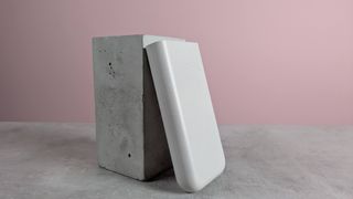 Samsung 45W 20000mAh Battery Pack leaning on plinth, on desk with pink background