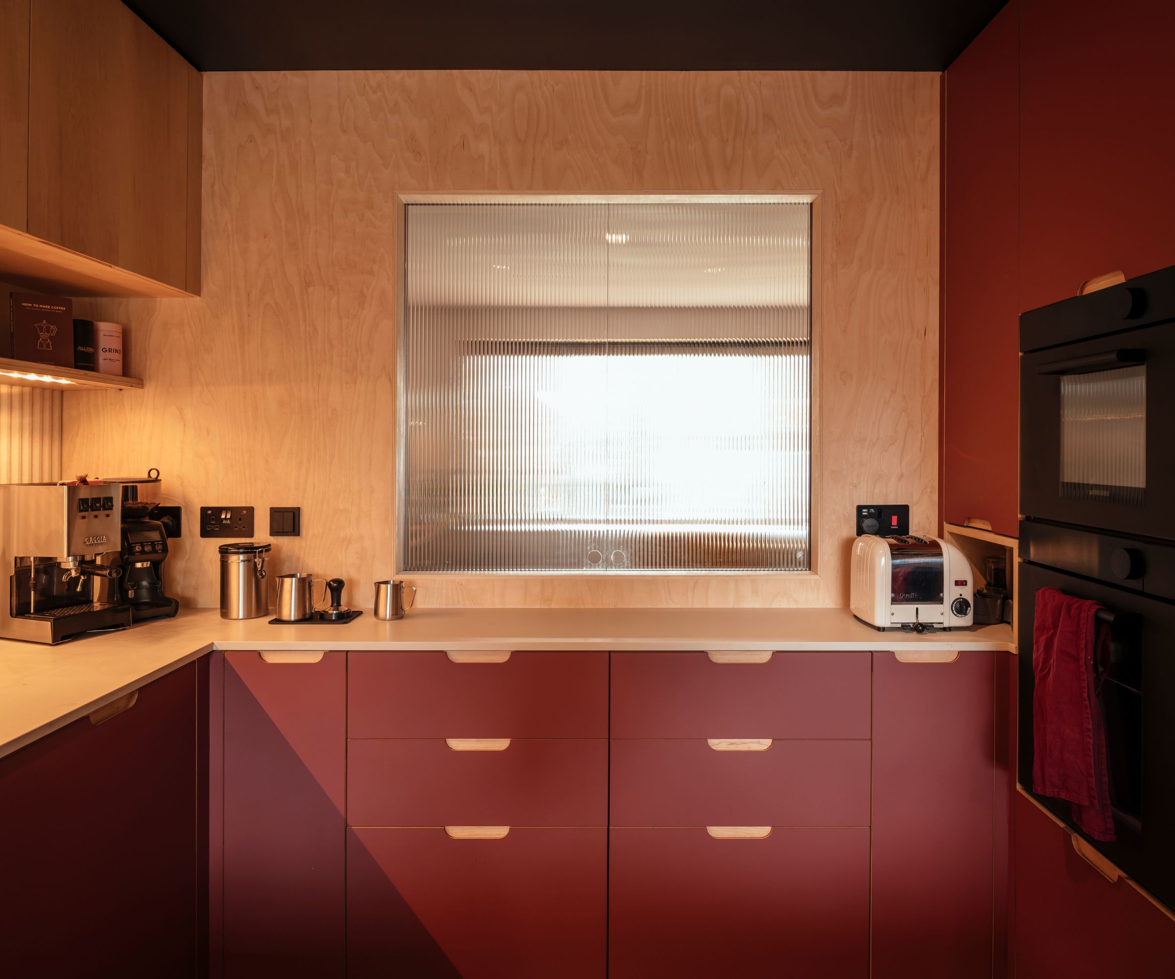 A burgundy scandi kitchen with a hatch featuring reeded glass pocket doors