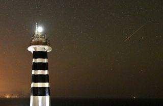 Perseid meteor on the right and a bright lighthouse painted black and white striped on the left.