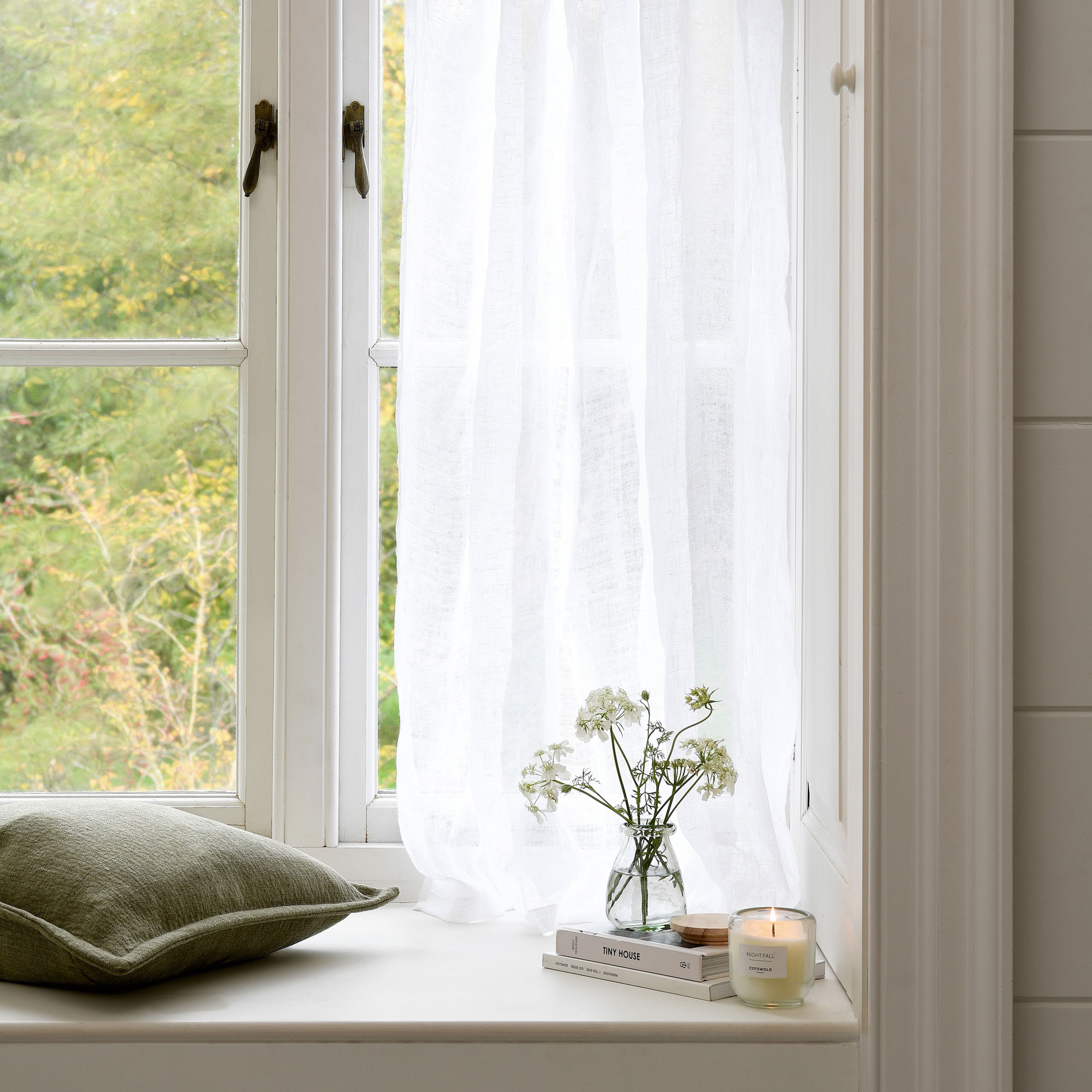 White window ledge with green cushion and voile curtain